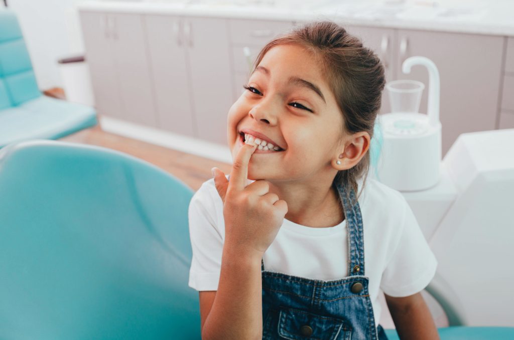 Child pointing at teeth in dentists chair
